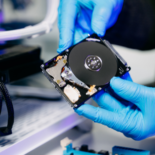 Technician or user holding a bare hard drive ready for assessment.