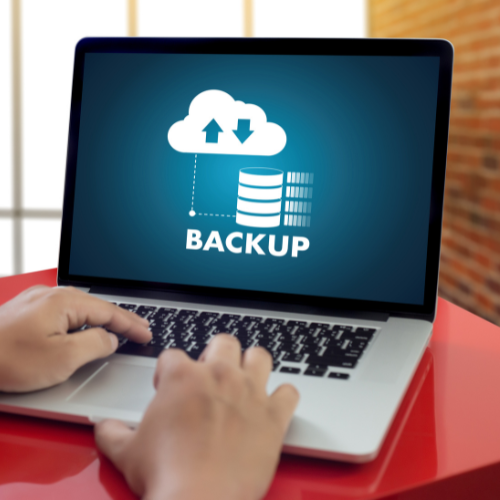 Hands typing on a laptop with backup software visible on the screen.