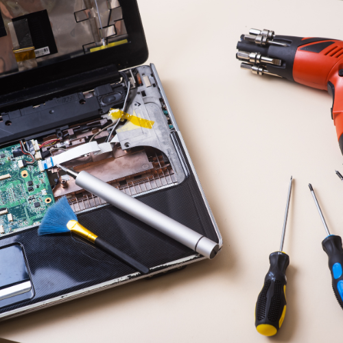 Laptop partially disassembled on a workbench with tools during repair assessment.
