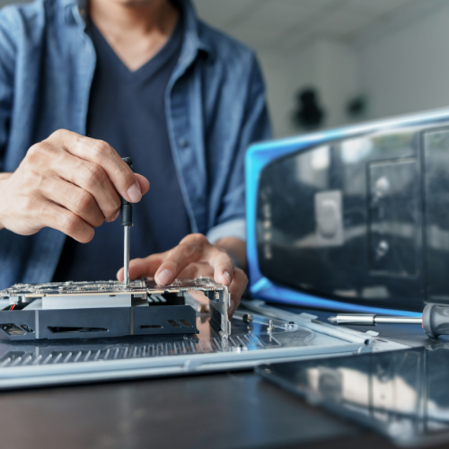 Technician working on a desktop graphics card with a PC case in the background.